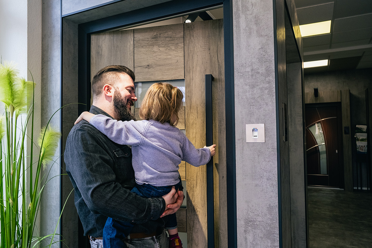 Glücklicher Kunde mit Kind bei der Auswahl von Haustüren im Ausstellungsraum